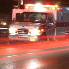 Ambulance driving down road with lights on.