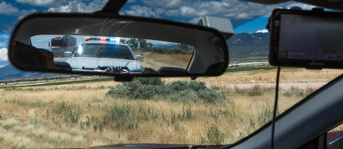 police car with siren on in a rearview mirror