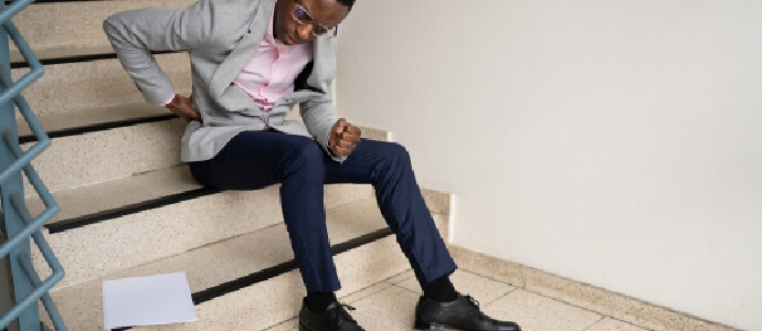 a man holding his back while sitting on stairs