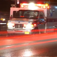 Ambulance driving down road with lights on.