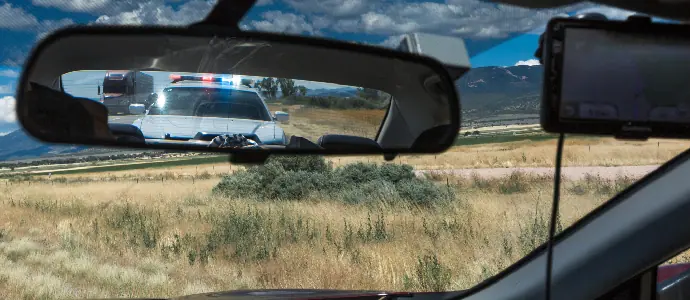 police car with siren on in a rearview mirror