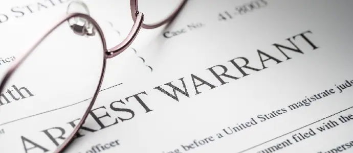 an arrest warrant with a pair of glasses on top