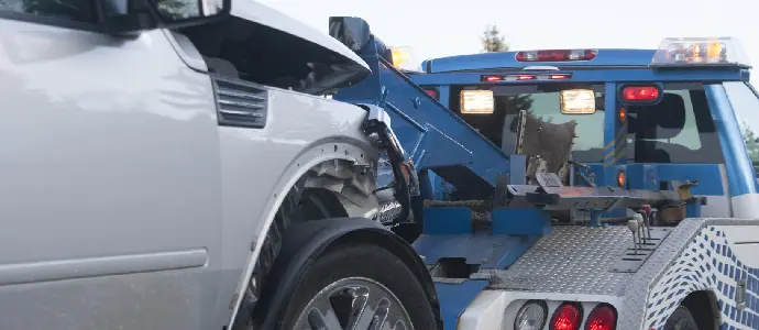 a dented front of a truck on a tow truck